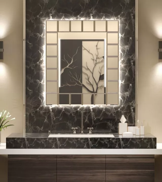 A bathroom in Victoria features a backlit mirror over a sink set into a wall of black ceramic tiles.