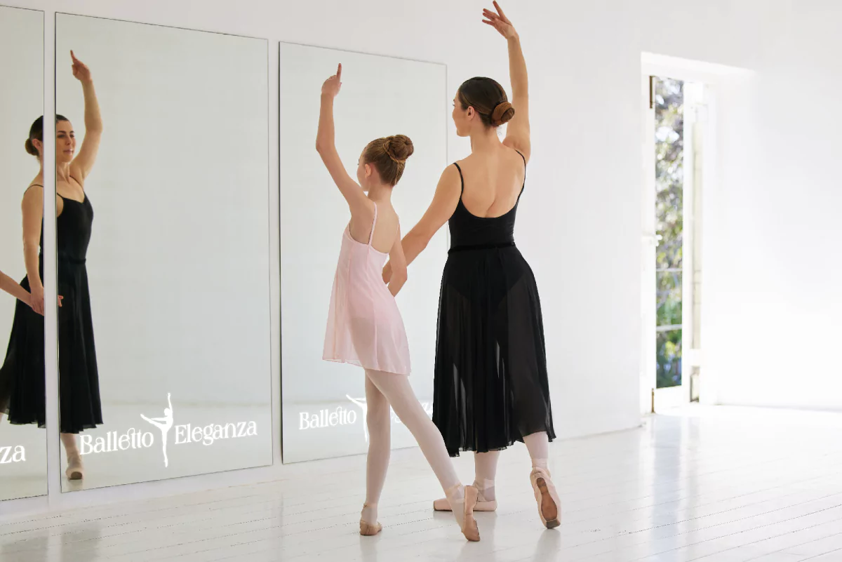 Ballet dancers practicing their moves in front of a mirror featuring LED light logo in Queensland.