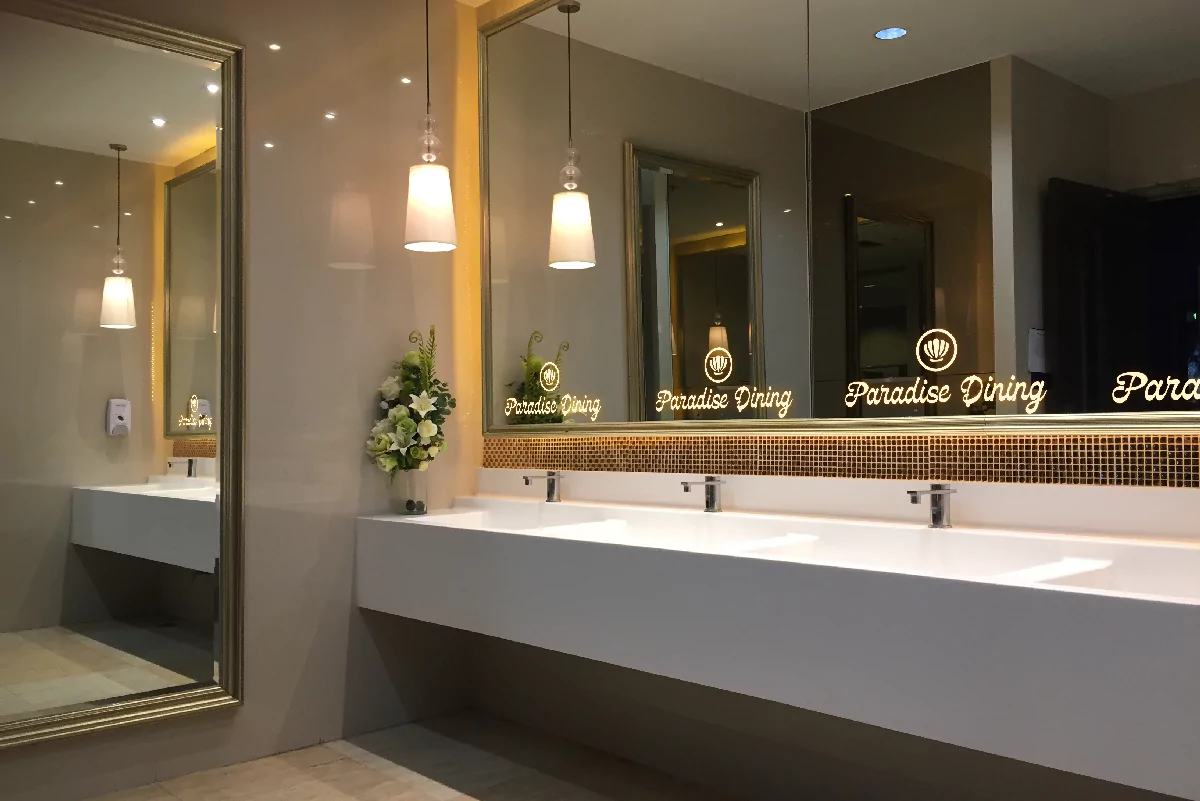 Bathroom interior with sinks and a mirror displaying a custom illuminated logo in Newcastle.