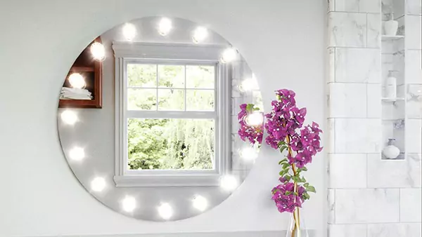 Round made to order hollywood mirror with LED lights in a bright bathroom with purple flowers in Melbourne.