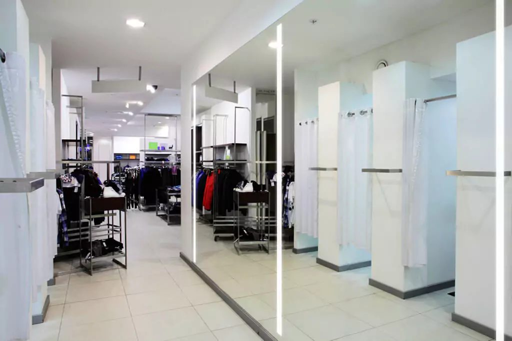 Clothing store with various garments hanging on racks reflected in a lighted mirror in Canberra.