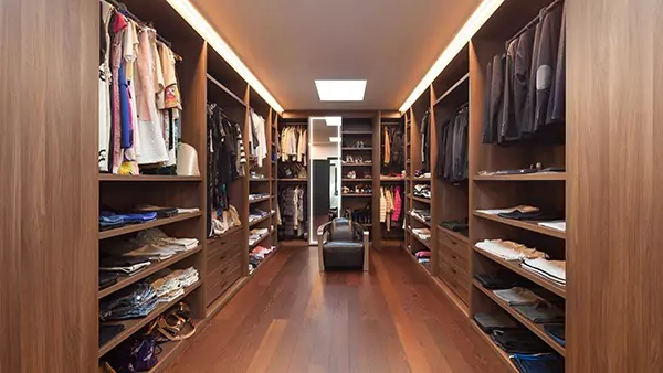 Compact of interior of a walk in closet with wooden shelves and a luminous mirror in Lismore.