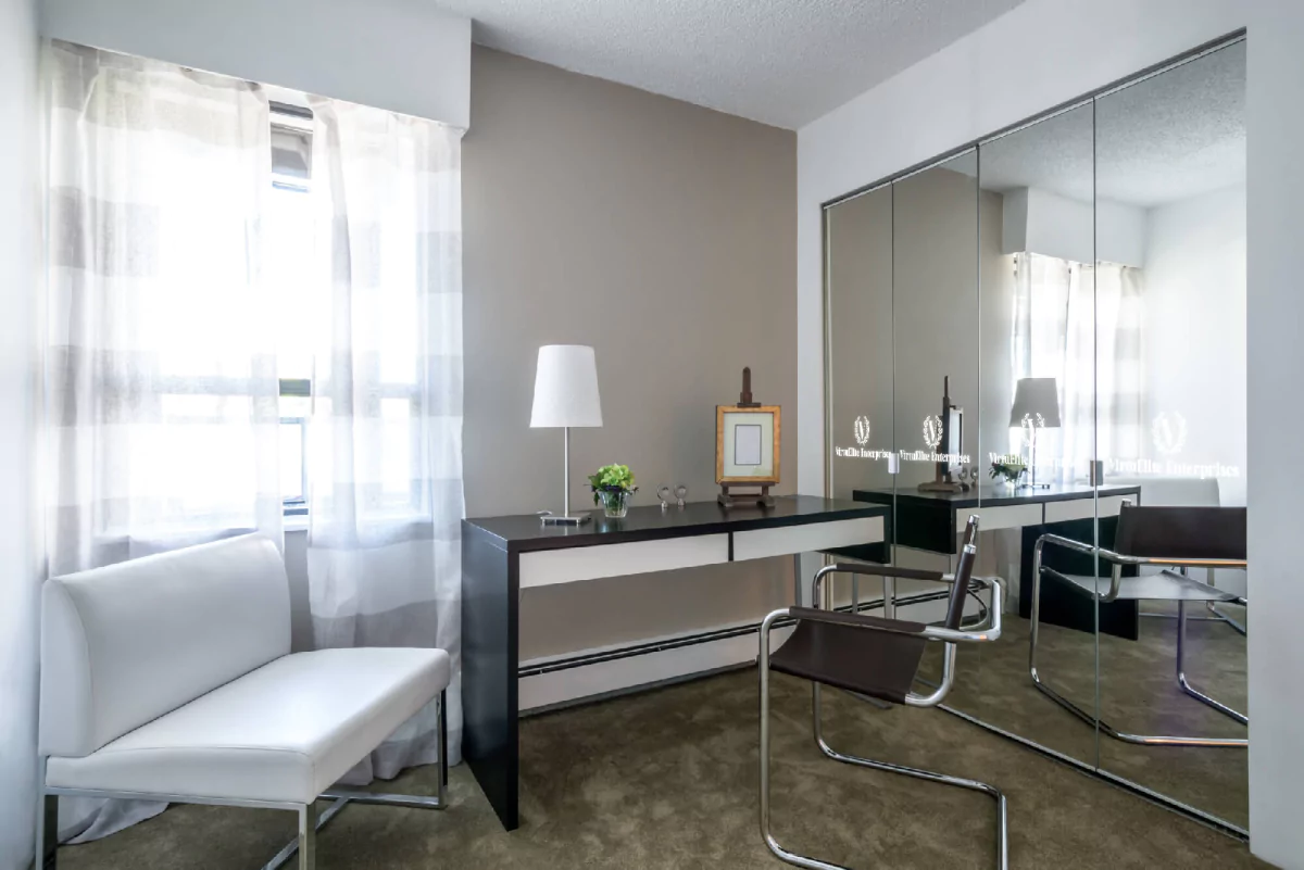 Cozy work office with a white lampshade on the top of a desk and a full-length mirror wall in Perth.