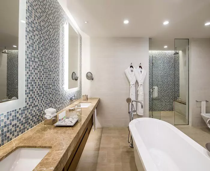 A bathroom with a lighted frosted mirror and a bathtub in Canberra.