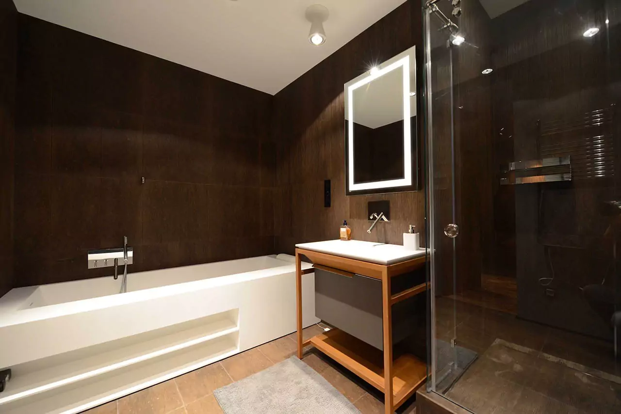 Luminous mirror brightens dimmed bathroom with wooden sink and shower in Hobart.