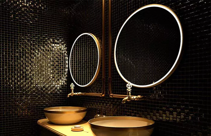 A dark themed bathroom with two sinks and rounded mirrors in Melbourne.