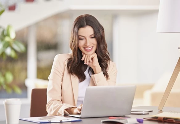 A woman in Gold Coast sitting at a desk, working on a laptop computer.