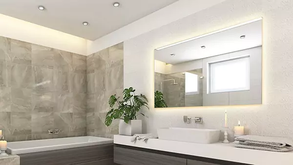 An updated bathroom showcasing a big lighted mirror and tub in Queensland.