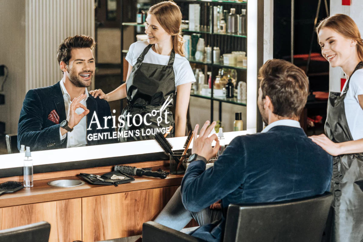 A woman admiring a man's hair reflecting in a mirror with an illuminated logo in Melbourne.