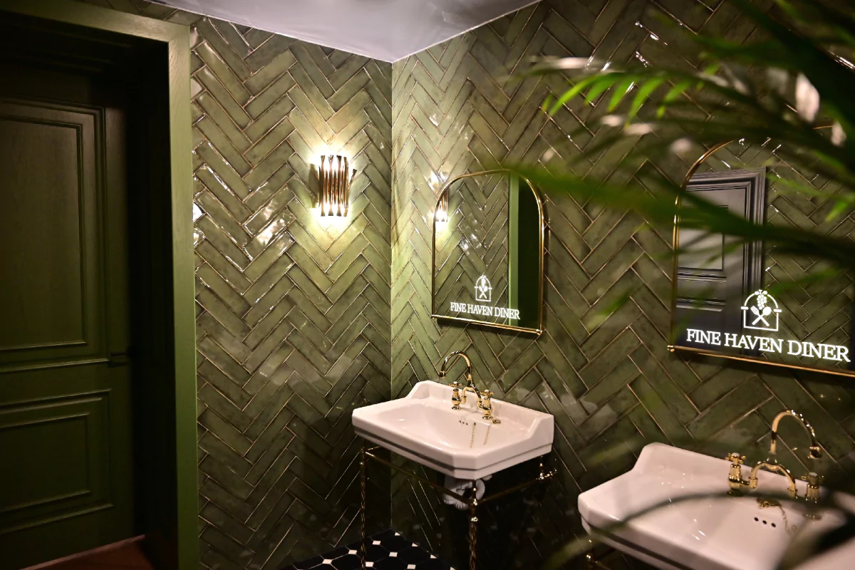 Green tiled bathroom with a mirror displaying a custom lighted logo in Melbourne.