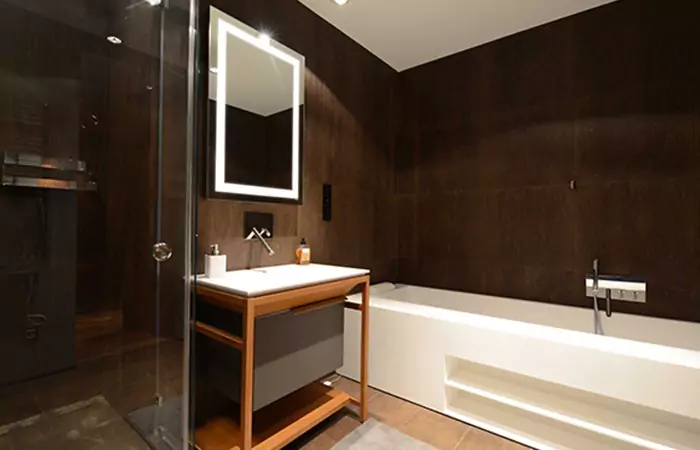 Classy restroom with a bathtub and wall mounted led mirror above wooden sink in Lismore.