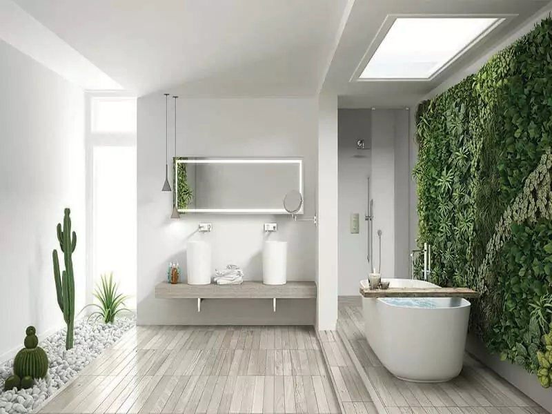 A bathroom with a bathtub at the side of an illuminated mirror that is set above the double sinks.