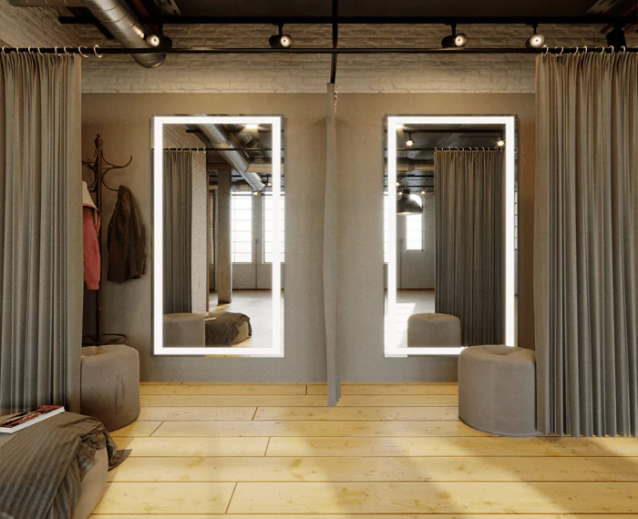 Two full length illuminated mirrors in a fitting room with a brown round foam stool in Victoria.