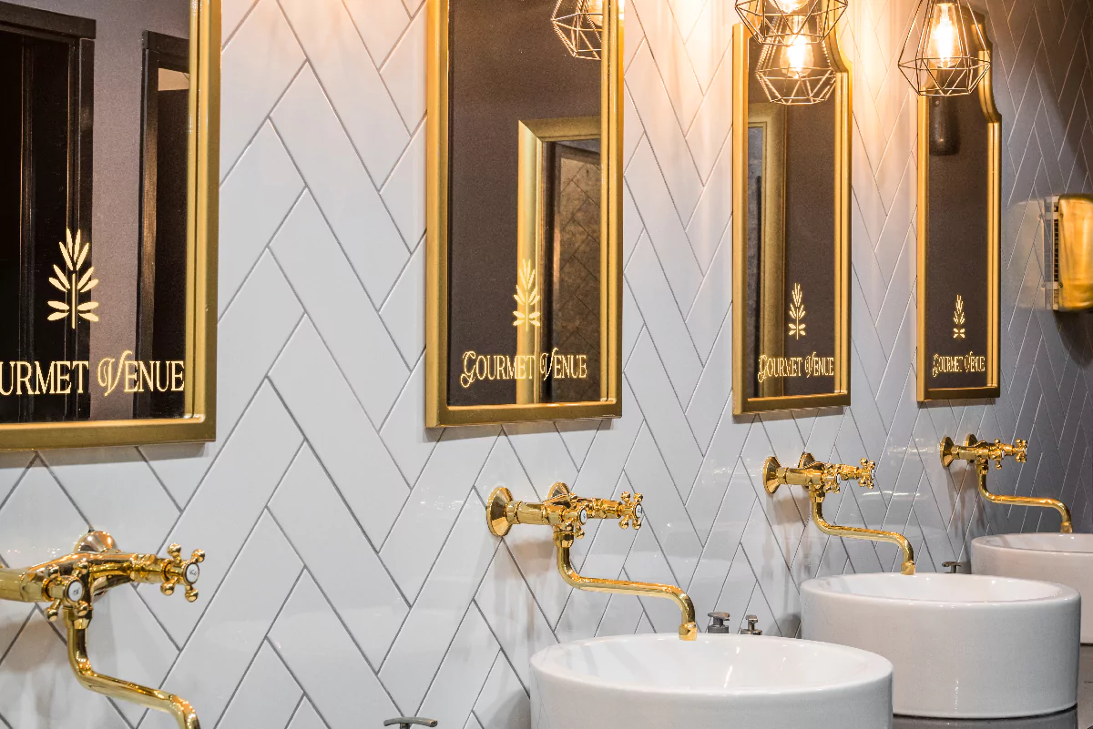 Luxurious bathroom with gold fixtures and mirrors with a lighted logo in Victoria.