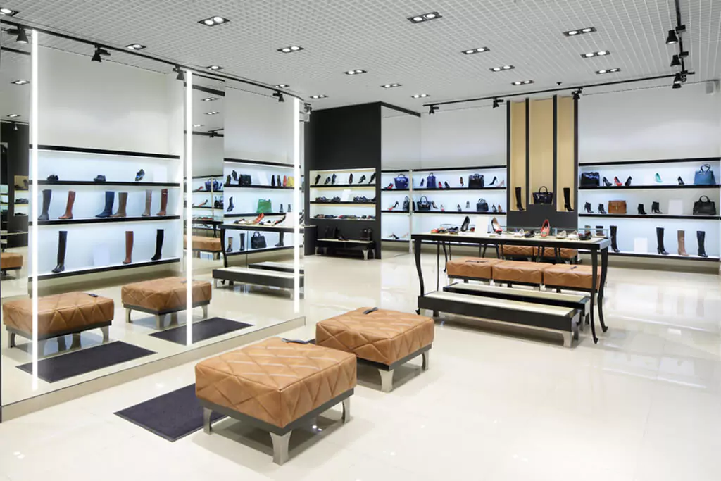 A shoe store's setup includes large lighted mirrors and stools for trying on items in Lismore.