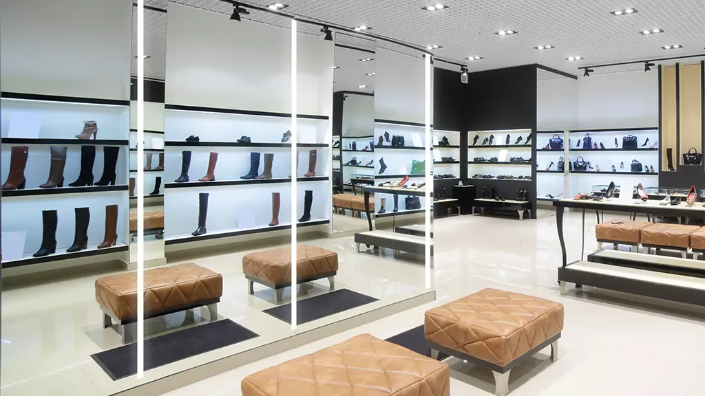 Interior of a shoe store featuring a large lighted mirror and a leather bench in Hobart.