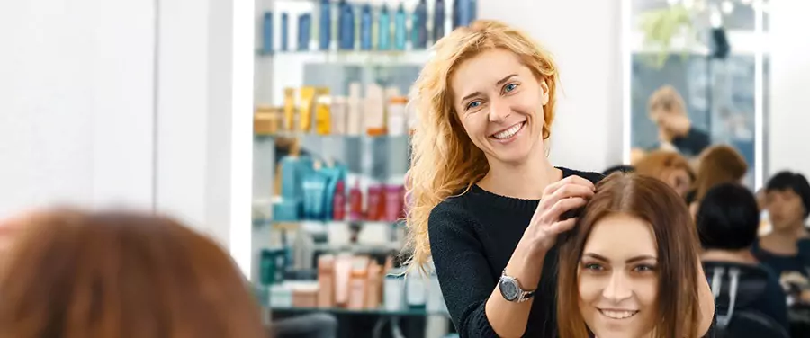 A woman with a joyful expression getting her hair cut by a professional hairstylist in Sydney.